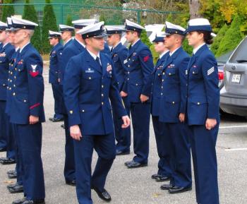 Coast Guard Station Boothbay Harbor: Officer in Charge BMC Kris Demetros, assisted by Executive Petty Officer BM1 James Zerinskas, inspects station personnel during Wednesday morning’s Call to Colors. Coinciding with a weekly all-hands assembly known as “Quarters,”  a periodic dress uniform inspection imparts a formal note to the daily raising of the American flag. Courtesy of Ted Chatham, USCG Auxiliary